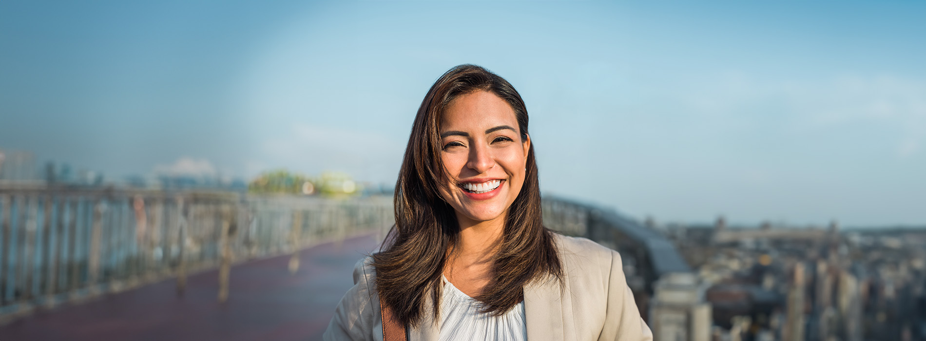 The image is a photograph of a woman with light skin, smiling at the camera. She appears to be in her late twenties or early thirties and has long hair. Her eyes are looking directly at the camera, and she is holding up her index finger near her mouth as if she s making a point or emphasizing something. The background is plain and light-colored, which suggests that this could be a stock photo used for various purposes such as advertising, personal branding, or lifestyle content.